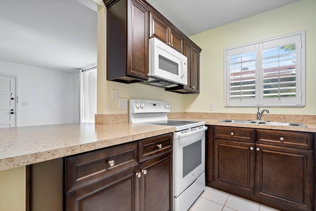 kitchen with dark brown cabinets, white appliances, sink, and light tile patterned floors