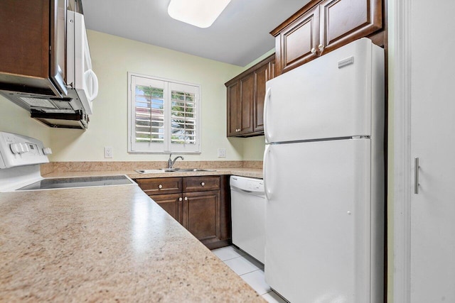 kitchen featuring light tile patterned flooring, dark brown cabinetry, white appliances, and sink