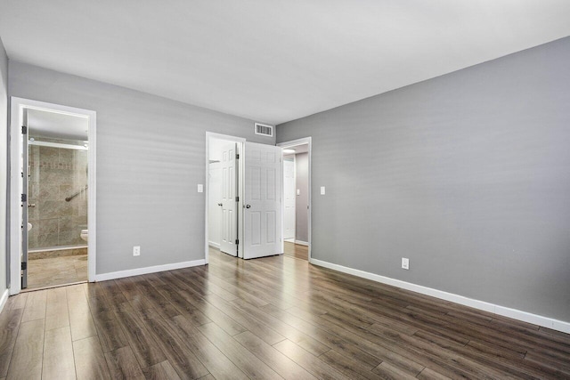 unfurnished bedroom with connected bathroom and dark hardwood / wood-style flooring