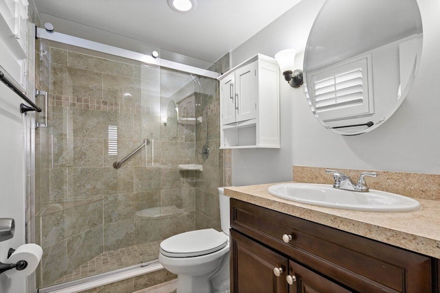 bathroom with vanity, a shower with shower door, and toilet