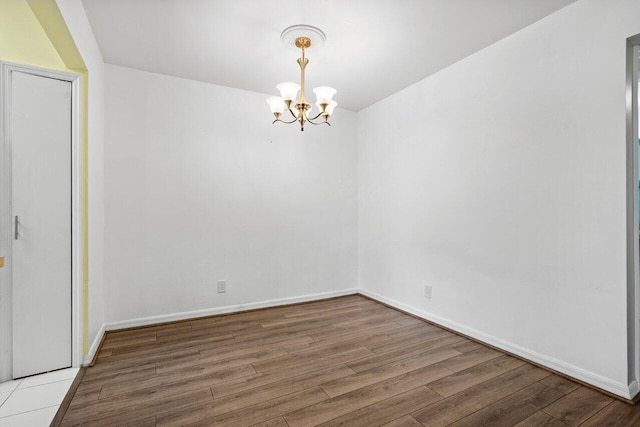 empty room featuring a chandelier and hardwood / wood-style flooring