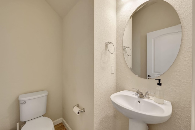 bathroom with sink, toilet, and vaulted ceiling