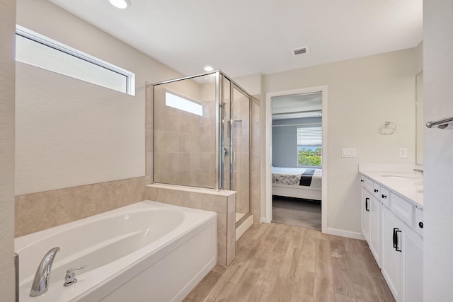 bathroom with vanity, wood-type flooring, a wealth of natural light, and independent shower and bath