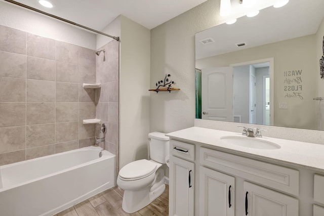 full bathroom featuring tiled shower / bath combo, wood-type flooring, vanity, and toilet