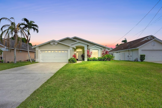 single story home with driveway, a lawn, an attached garage, and stucco siding