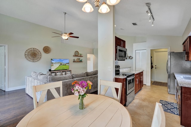 dining space featuring baseboards, visible vents, light tile patterned flooring, track lighting, and ceiling fan with notable chandelier