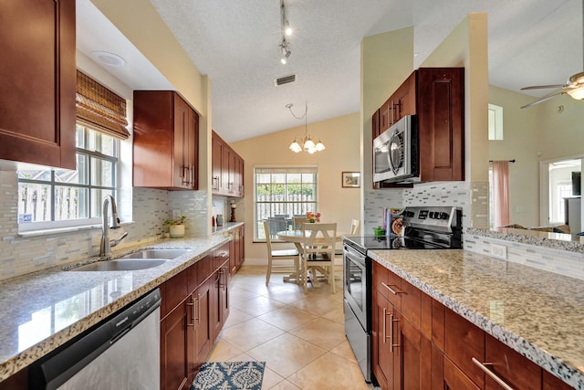 kitchen featuring light stone counters, visible vents, hanging light fixtures, appliances with stainless steel finishes, and a sink