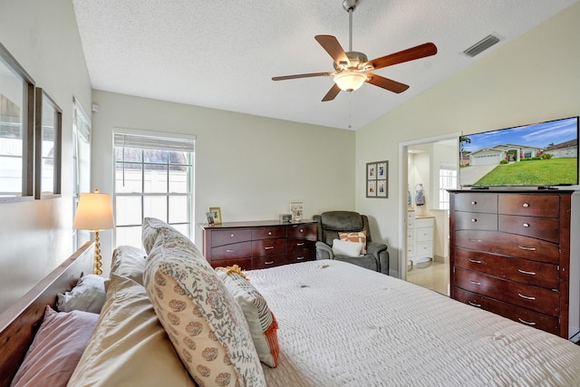 bedroom with visible vents, a ceiling fan, ensuite bath, vaulted ceiling, and a textured ceiling