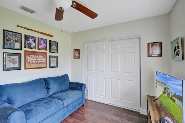 living area featuring ceiling fan, visible vents, and dark wood-type flooring