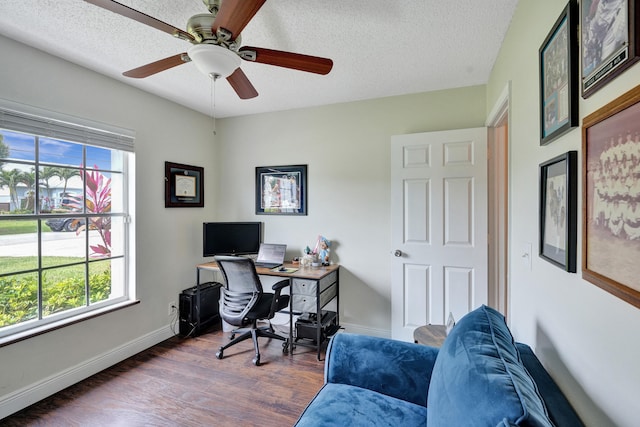 office area with a textured ceiling, dark wood-type flooring, a wealth of natural light, and baseboards