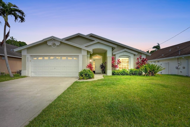 ranch-style house with driveway, a yard, an attached garage, and stucco siding