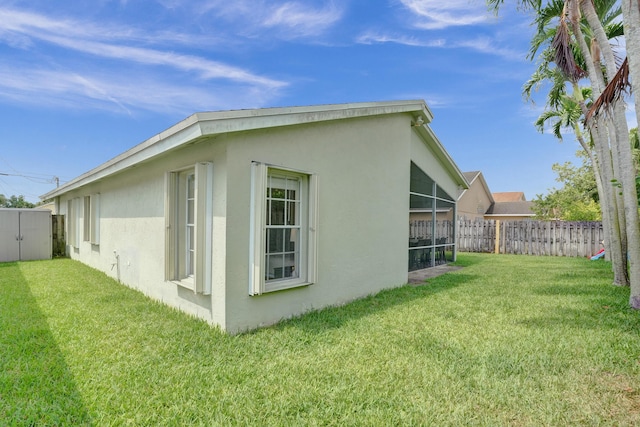 view of property exterior featuring stucco siding, a yard, and fence