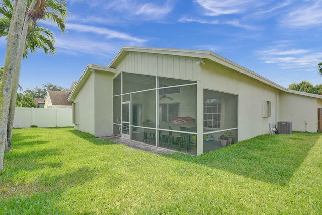 rear view of house with cooling unit, stucco siding, a lawn, and fence