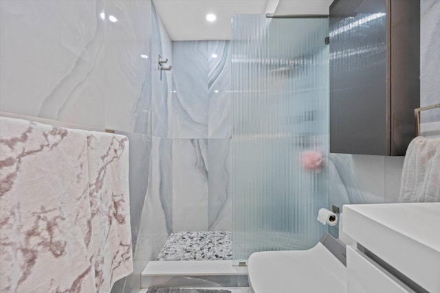 bathroom featuring a shower with door, vanity, tile walls, and toilet