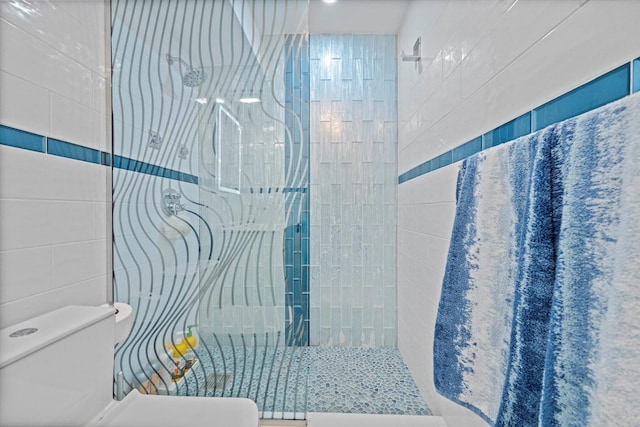 bathroom with vanity, a shower with door, decorative backsplash, toilet, and tile walls