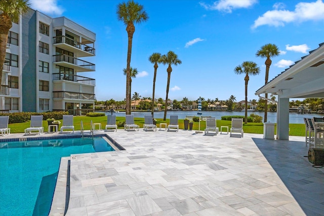 view of pool with a lawn, a patio area, and a water view