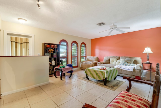 living room featuring tile floors, a textured ceiling, and ceiling fan