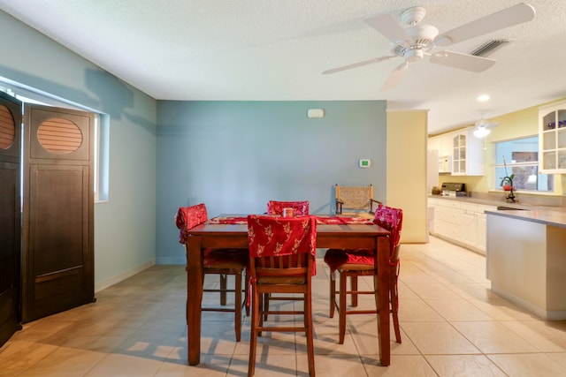 dining space with sink, a textured ceiling, ceiling fan, and light tile floors