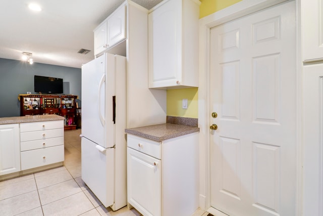 kitchen featuring white refrigerator, white cabinetry, and light tile floors