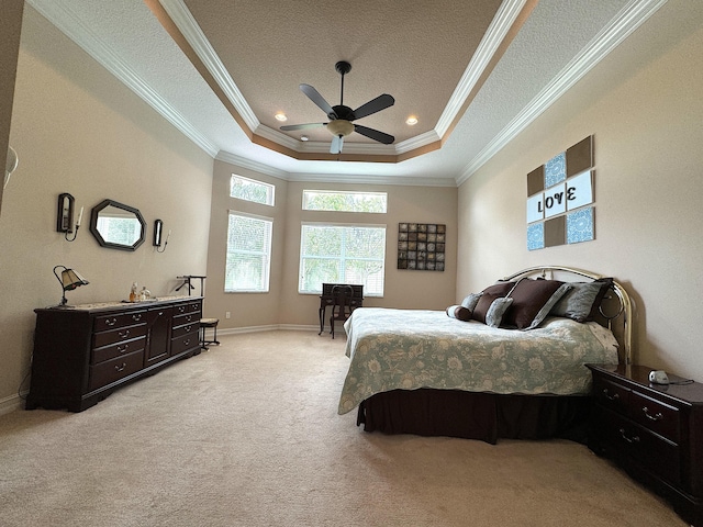 bedroom with ceiling fan, a textured ceiling, a tray ceiling, light carpet, and ornamental molding