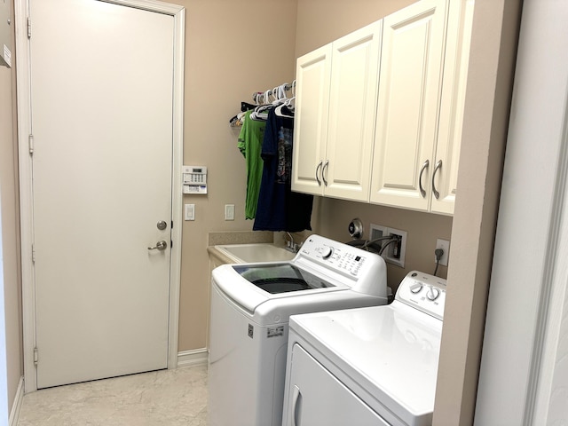 laundry area featuring cabinets, separate washer and dryer, and sink