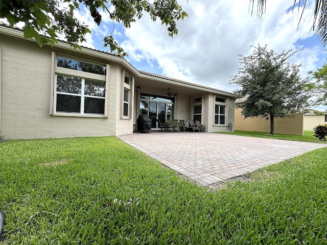 rear view of property featuring a patio area, ceiling fan, and a yard