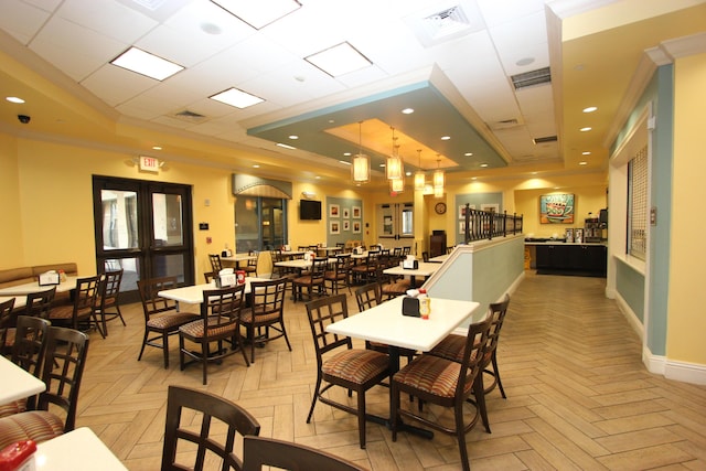 dining area featuring a tray ceiling, light parquet floors, and ornamental molding