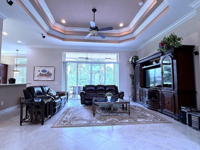 living room with a raised ceiling, ceiling fan, and crown molding