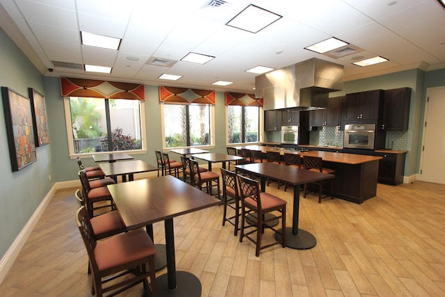 dining space featuring a paneled ceiling, light hardwood / wood-style flooring, and crown molding