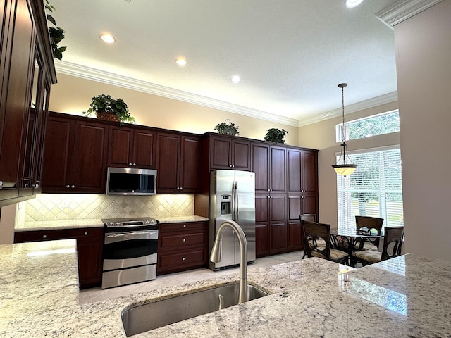 kitchen with pendant lighting, crown molding, sink, appliances with stainless steel finishes, and light stone counters