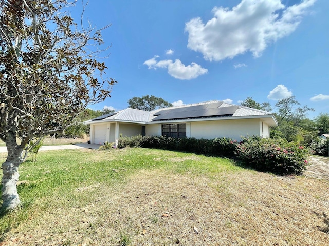 single story home featuring solar panels, a garage, and a front lawn