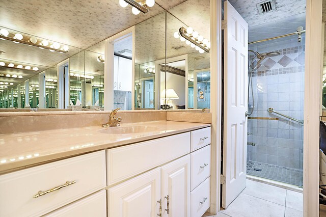 bathroom featuring a shower with shower door, tile flooring, and vanity with extensive cabinet space