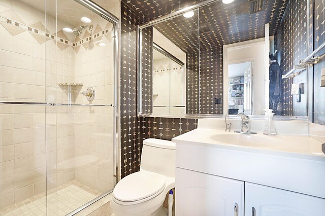 bathroom with a shower with door, toilet, and vanity with extensive cabinet space