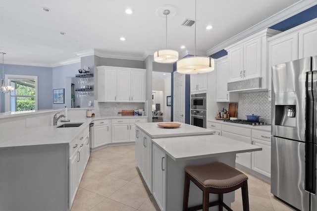 kitchen featuring light tile flooring, backsplash, hanging light fixtures, appliances with stainless steel finishes, and a breakfast bar