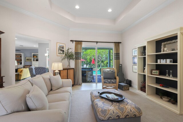 living room with crown molding, built in shelves, and a raised ceiling