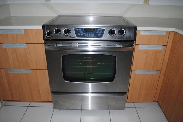 room details featuring stainless steel electric range oven and light tile patterned floors