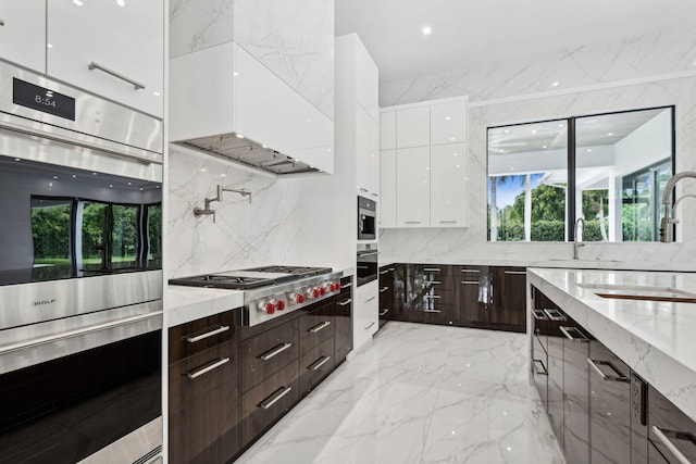 kitchen with white cabinets, appliances with stainless steel finishes, light stone counters, and plenty of natural light