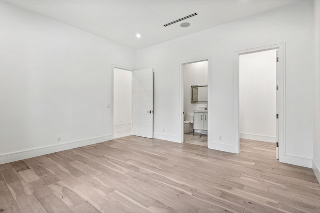 unfurnished bedroom featuring connected bathroom and light hardwood / wood-style flooring