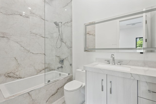 full bathroom featuring vanity, tiled shower / bath combo, and toilet