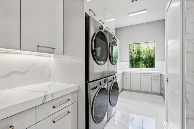 laundry room with cabinets and stacked washer / drying machine