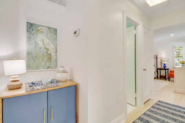 corridor with light wood-type flooring and crown molding