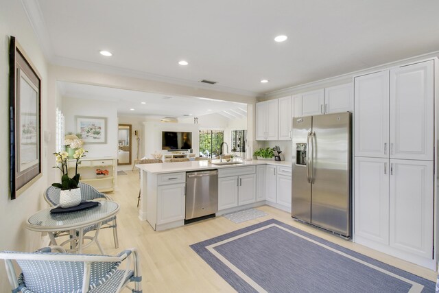 kitchen featuring kitchen peninsula, light wood-type flooring, sink, white cabinets, and appliances with stainless steel finishes