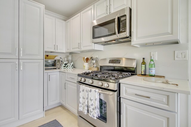 kitchen with light wood-type flooring, white cabinetry, and appliances with stainless steel finishes