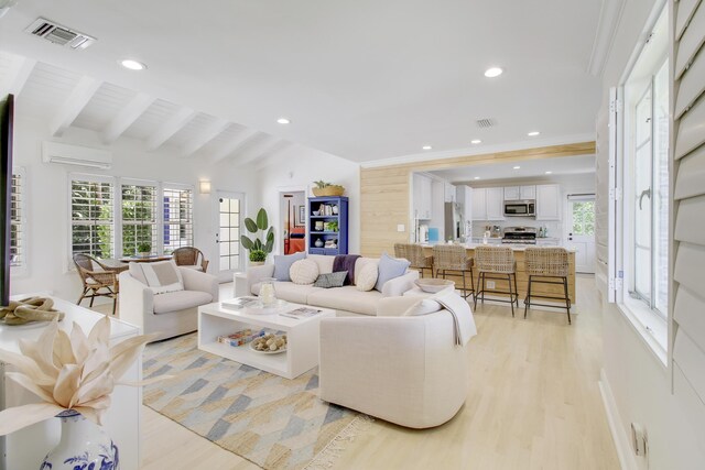 living room with a healthy amount of sunlight, vaulted ceiling with beams, and light wood-type flooring