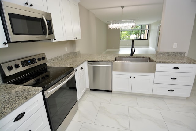 kitchen with kitchen peninsula, pendant lighting, white cabinets, and stainless steel appliances