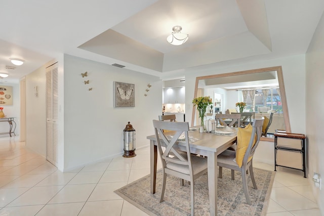 tiled dining area featuring a tray ceiling