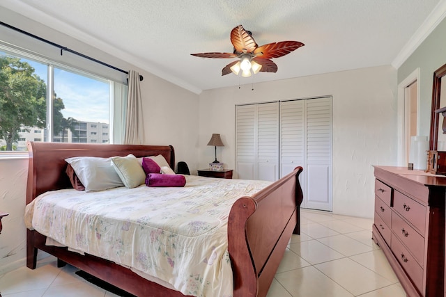 tiled bedroom with ceiling fan, ornamental molding, a textured ceiling, and a closet