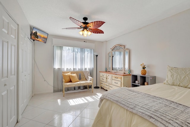 bedroom with light tile patterned floors, a textured ceiling, a closet, and ceiling fan