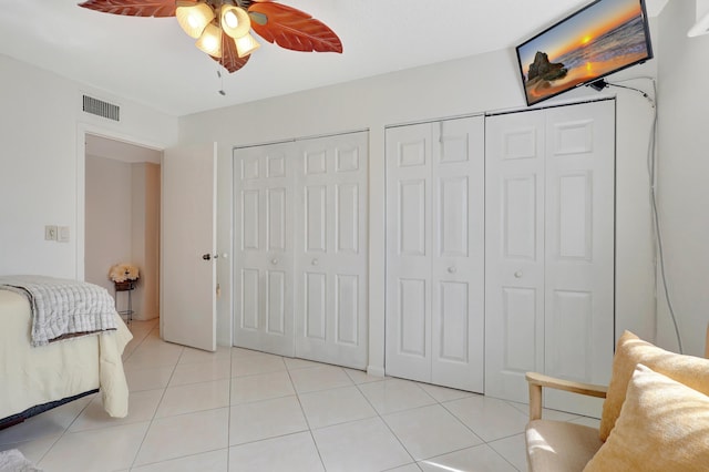 bedroom featuring light tile patterned floors, two closets, and ceiling fan