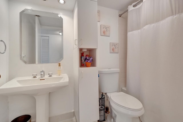 bathroom featuring a shower with curtain, toilet, and sink